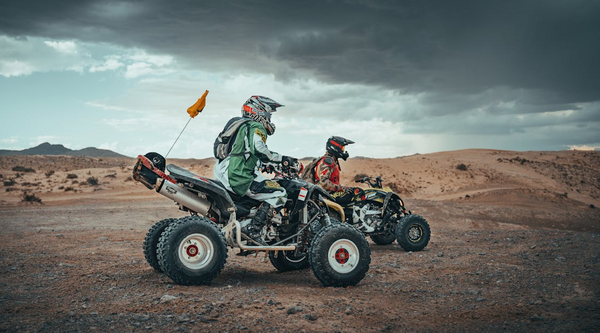 Two riders on quad bikes in the desert