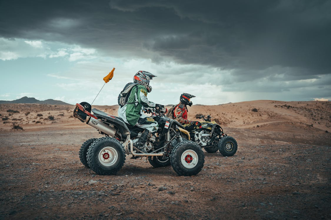 Two riders on quad bikes in the desert